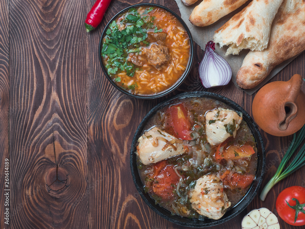 Φωτογραφία Traditional Georgian kitchen - spicy Kharcho soup and chicken Chachochbili, traditional bread Shotis Puri, vintage wine jar, fresh vegetables on wooden table