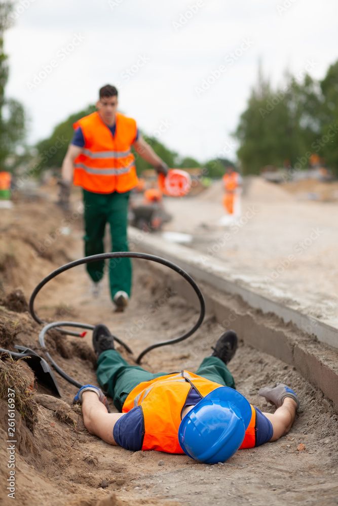 Accident during road construction, injured worker lying on the ground Accident during road construction, injured worker lying on the ground