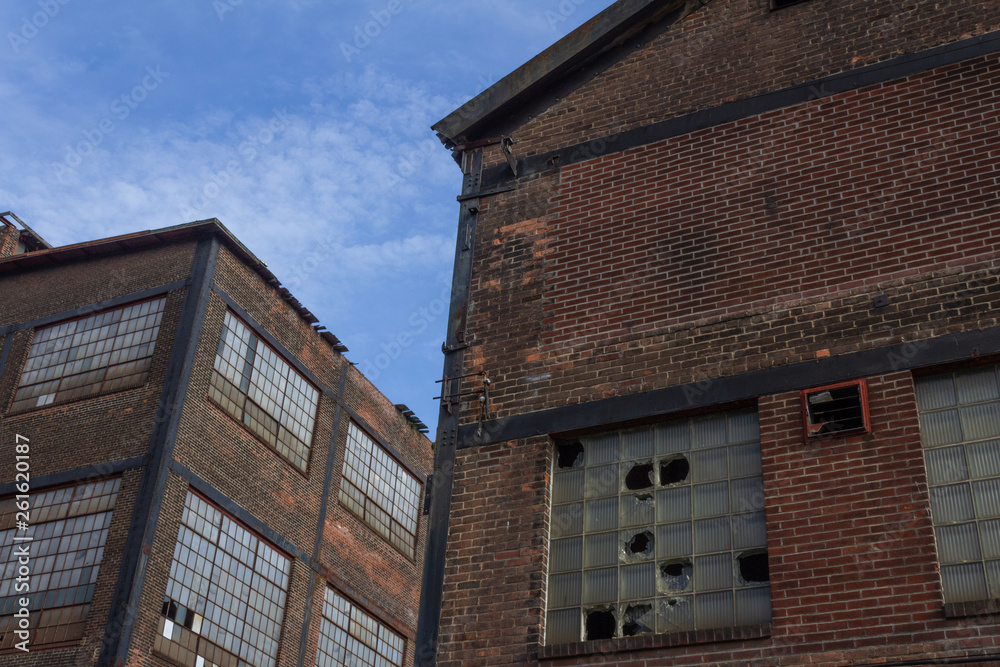 Two abandoned industrial buildings against a blue sky, horizontal aspect