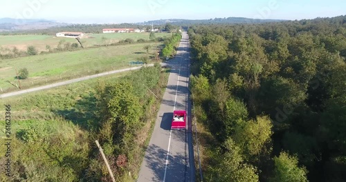 red classic car on the way to forest