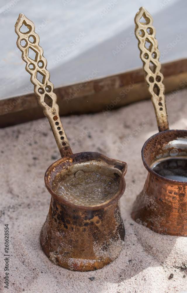 Close up view of turkish coffee prepared on hot golden sand. Close up view of turkish coffee prepared on hot golden sand.