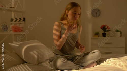 Sad female teenager chewing donut feeling stomach pain, stress overeating health photo