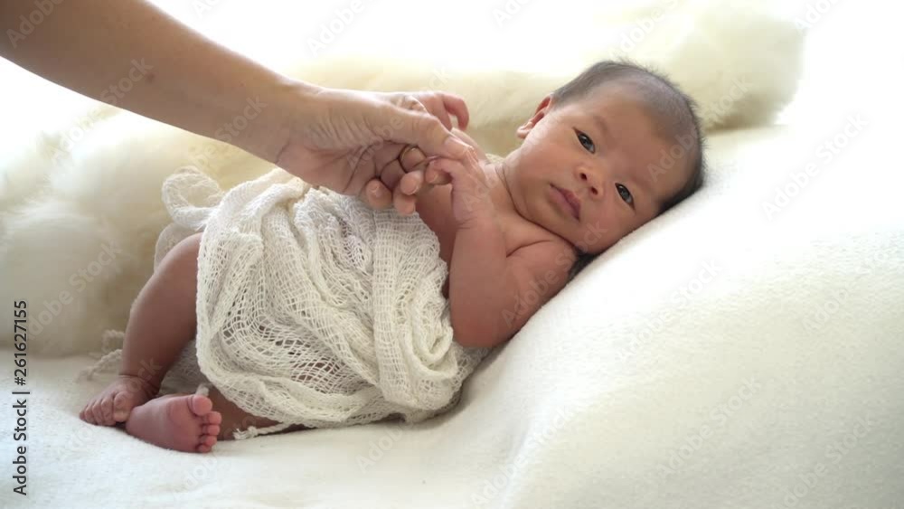 4K Video Selective focus stabilize medium shot of asian mother hand holding her newborn baby's hand that laying down on the white bed. Child hand into her mother hand together. 4K Video Selective focus stabilize medium shot of asian mother hand holding her newborn baby's hand that laying down on the white bed. Child hand into her mother hand together.