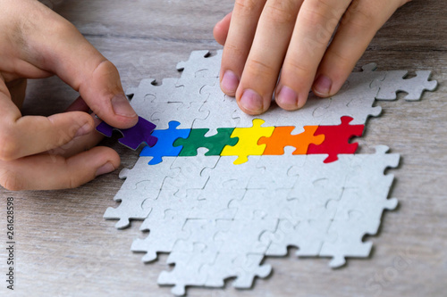 sex education in the spirit of equality and tolerance: a student builds a LGBT pride flag of the puzzle, short focus, top view
