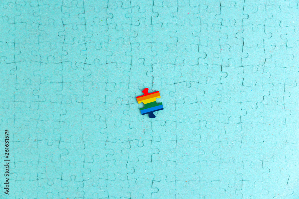 concept: LGBT as a part of society - one puzzle with the coloring of the flag of sexual minorities on a turquoise mosaic surface