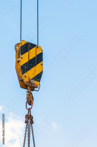 building construction: crane hook, chain and cables against the blue sky
