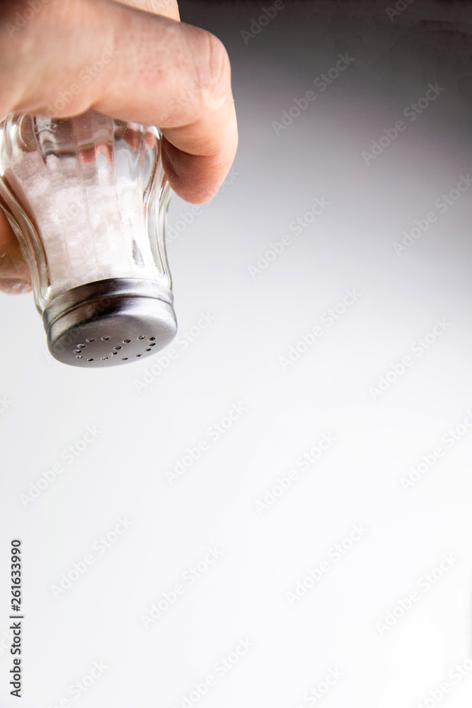 excess salt: saltcellar with the letter S in a man's hand, on a white background excess salt: saltcellar with the letter S in a man's hand, on a white background