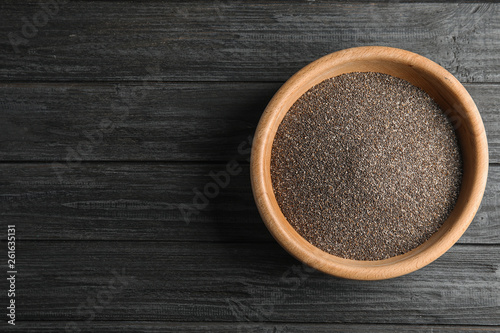 Bowl with chia seeds on wooden background, top view. Space for text