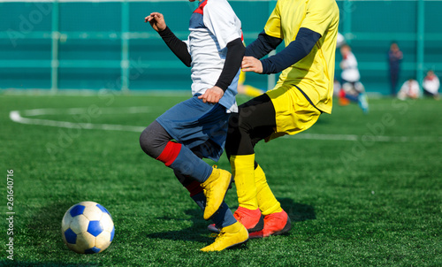 Fototapeta Naklejka Na Ścianę i Meble -  Boys in yellow white sportswear running on soccer field. Young footballers dribble and kick football ball in game. Training, active lifestyle, sport, children activity concept 
