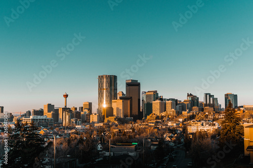 Calgary skyline in the early morning with rays from rising sun reflecting off glass buildings.