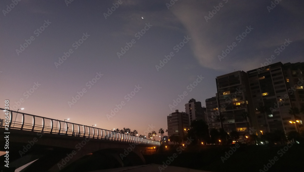 Naklejka premium Luna creciente al anochecer sobre el puente y el edificio