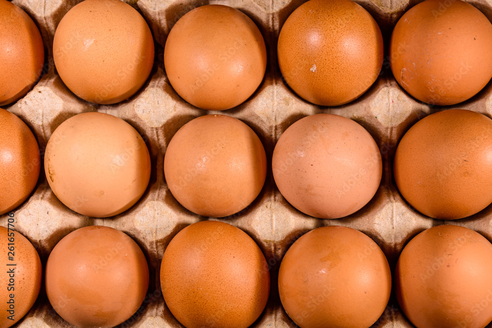 Pile of the hen eggs in paper tray on wooden table. Top view Pile of the hen eggs in paper tray on wooden table. Top view