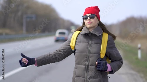 Young  pretty woman hitchhiking, stopping car. Steady shot photo