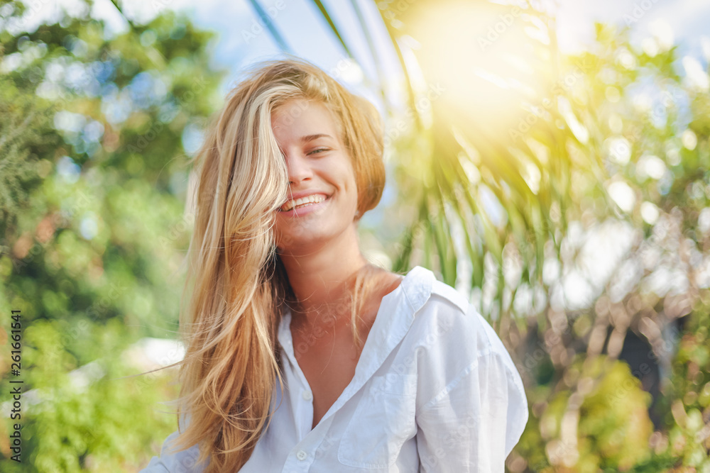 Portrait of cute blonde girl, face half covered with hair, enjoying nature in tropical garden, Portrait of cute blonde girl, face half covered with hair, enjoying nature in tropical garden,