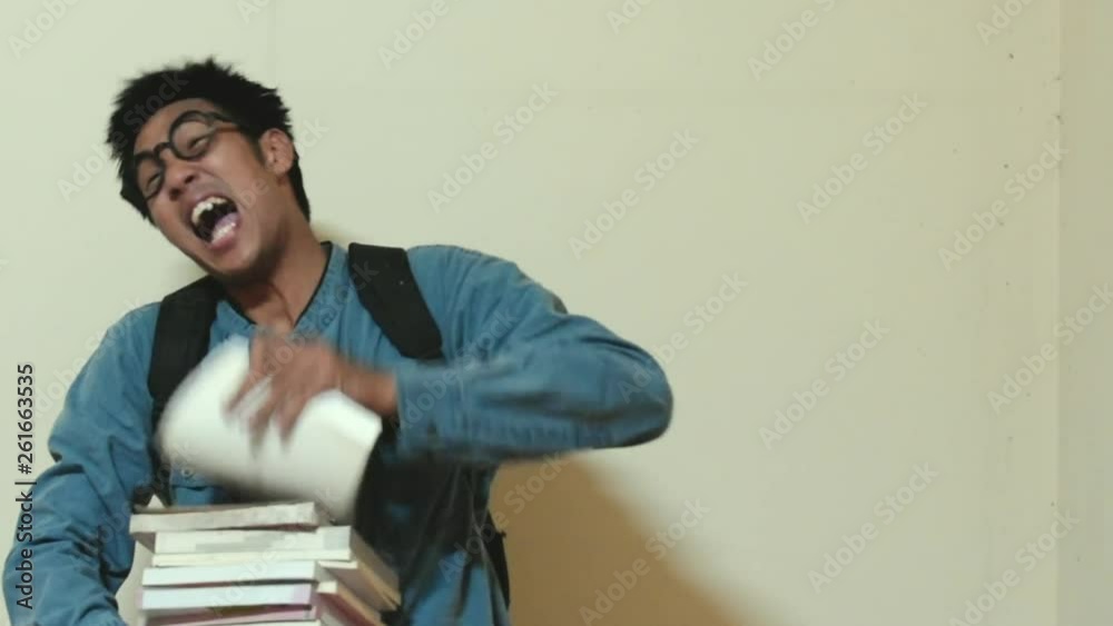 Man asian Overdo reading work without break For education to insupportable insufferable strain throwing the book on wall background Man asian Overdo reading work without break For education to insupportable insufferable strain throwing the book on wall background