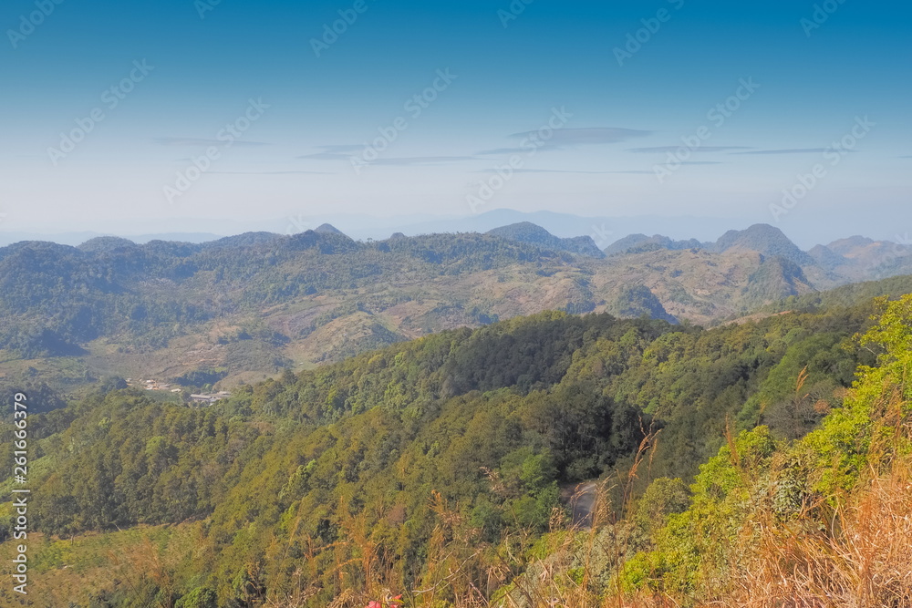 Mountain view morning on top of Doi Ang Khang above many hills and green forest cover with soft mist and blue sky background, Doi Angkhang, Chiang Mai, northern of Thailand.