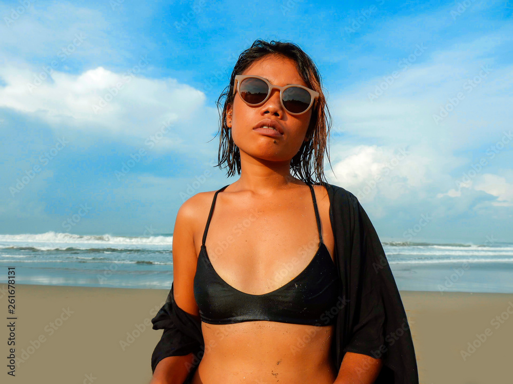 head and shoulders lifestyle portrait of young beautiful and sexy Asian girl in bikini and sunglasses enjoying holidays at tropical beach posing cool and confident at the sea head and shoulders lifestyle portrait of young beautiful and sexy Asian girl in bikini and sunglasses enjoying holidays at tropical beach posing cool and confident at the sea