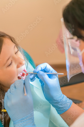 Little girl at the reception in the dentist s office. little girl sitting in a chair near a dentist after dental treatment. Little girl sitts in the dentist s office. vertical photo