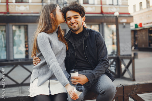 Cute couple in a spring city. Lady with long hair. Man in a black jacket. Two people with a coffee