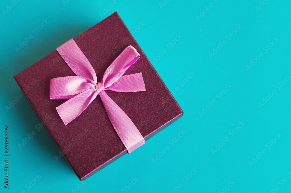 Small gift box with pink ribbon on background of turquoise color. Present for birthday, anniversary, christmas, etc. Small gift box with pink ribbon on background of turquoise color. Present for birthday, anniversary, christmas, etc.
