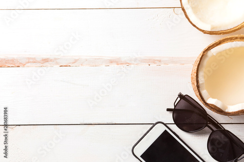 Phone, sunglasses, coconut cocktail on wooden background