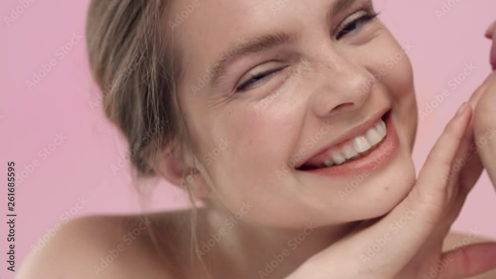 Young wide smiling woman looks at the camera on pink background Young wide smiling woman looks at the camera on pink background