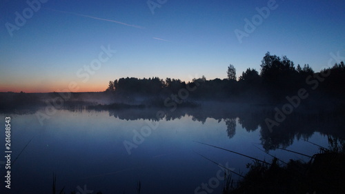 Morning dawn of the sun through the mist over the water. Early morning in the forest on the river.