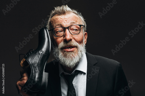 Fotografie Studio portrait of positive grey-bearded old man in black suit, white shirt and