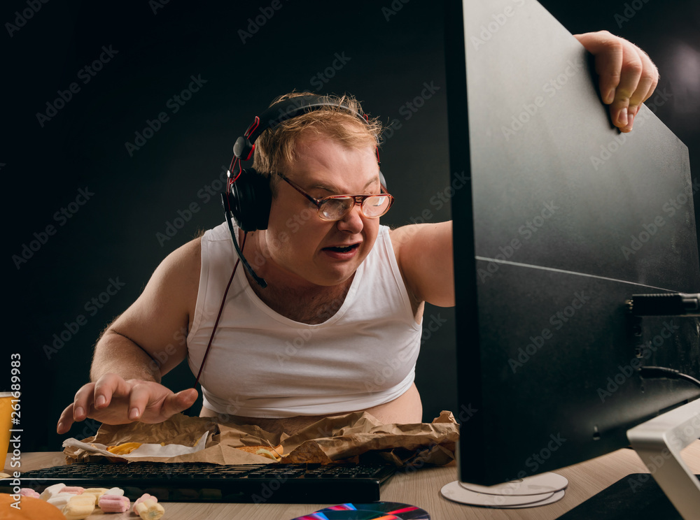 Guy Playing Computer Raging angry young man in headset playing game at home. close up photo ...