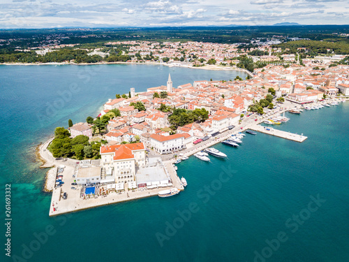 Croatian town of Porec, shore of blue azure turquoise Adriatic Sea, Istrian peninsula, Croatia. Bell tower, red tiled roofs of historical buildings, boat, piers. Euphrasian Basilica. Aerial view