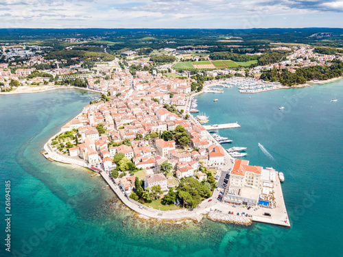 Croatian town of Porec, shore of blue azure turquoise Adriatic Sea, Istrian peninsula, Croatia. Bell tower, red tiled roofs of historical buildings, boat, piers. Euphrasian Basilica. Aerial view photo