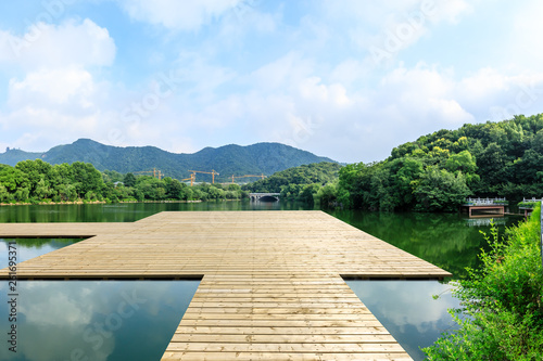 Wooden floor platform and lake with green mountains background in Hangzhou © ABCDstock