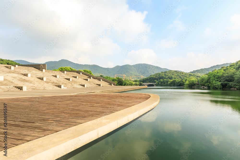 Fototapeta premium Wooden floor platform and lake with green mountains background in Hangzhou