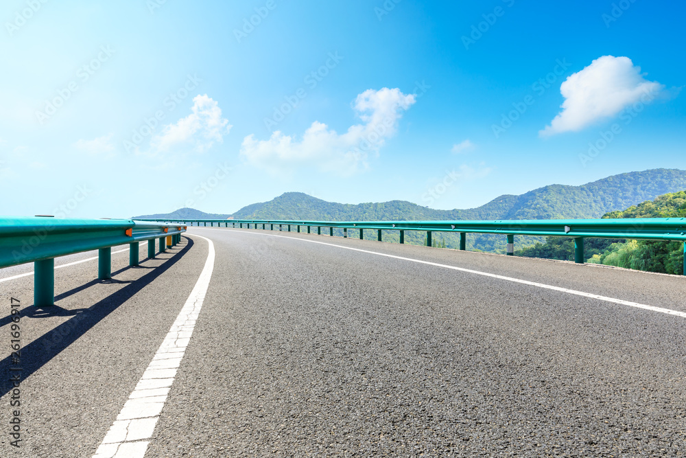 Empty asphalt road and mountains with blue sky on a sunny day