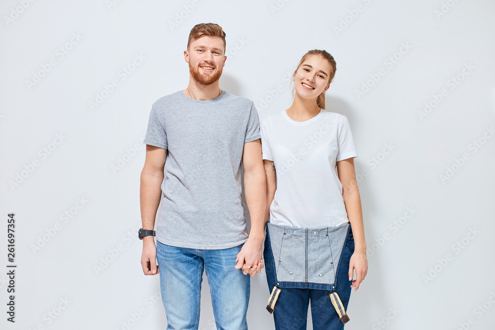 Cute young happy couple in love smiling holding hands looking at camera, isolated over white background Cute young happy couple in love smiling holding hands looking at camera, isolated over white background