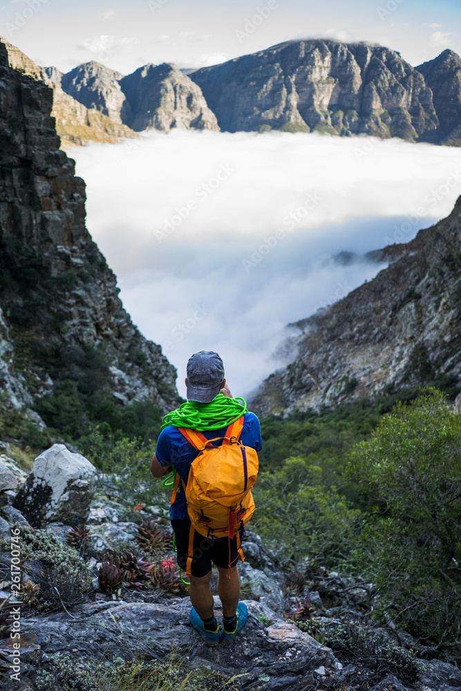 A climber watching the sunrise over a bank of clouds in the Cape mountains of South Africa