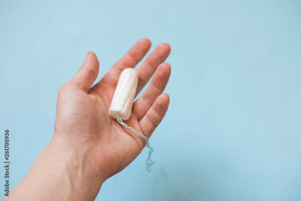 tampon menstrual cotton pads in woman hand on blue background copy space . Woman hygiene conception photo tampon menstrual cotton pads in woman hand on blue background copy space . Woman hygiene conception photo