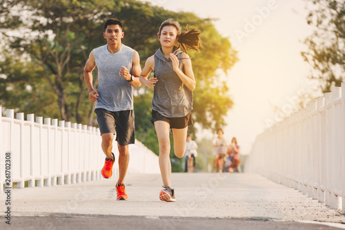 young couple runner running on running road in city park