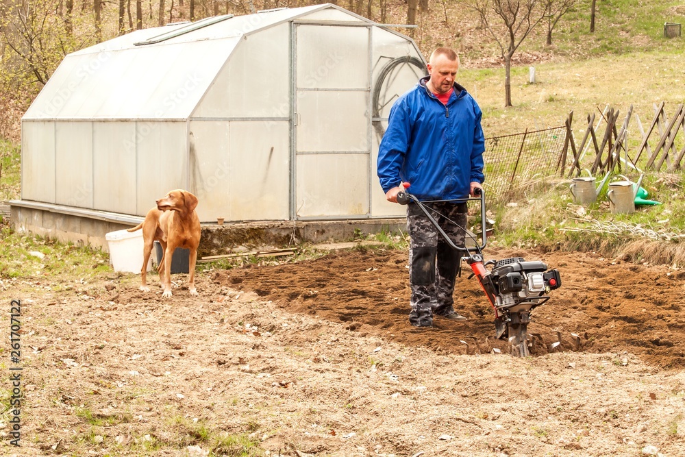 Spring preparation soil for seeding with tiller. Spring work in the garden. Farmer plows the