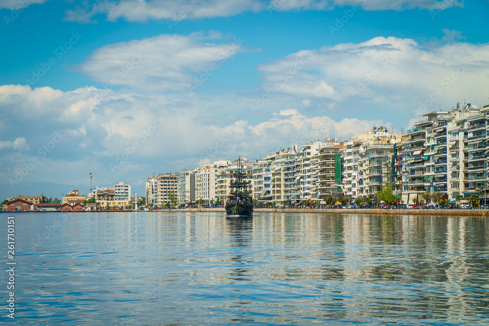 Thessaloniki / greece 11 april 2019 : midday shot of the sea of thessaloniki ,the port the buildings and the sun is making the day perfect after so much rain last week,a ship is approaching