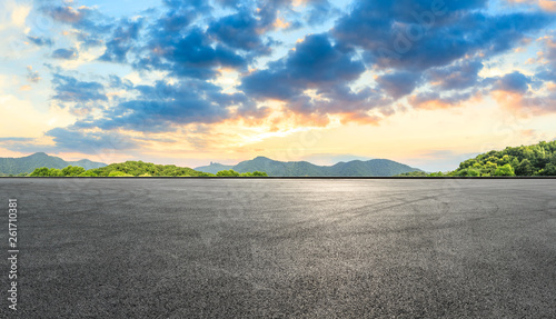 Asphalt race track ground and mountains with beautiful clouds at sunset © ABCDstock