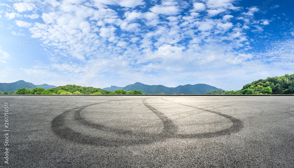 Fototapeta premium Asphalt race track ground and mountains with blue sky landscape
