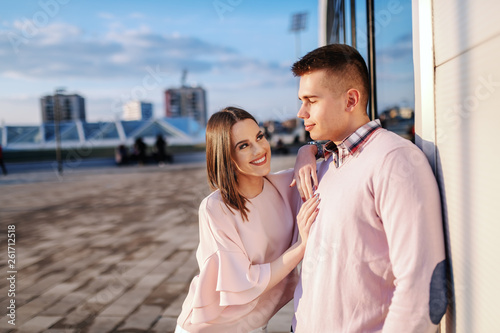 Young Caucasian fashionable couple standing outdoors, posing and looking at camera.