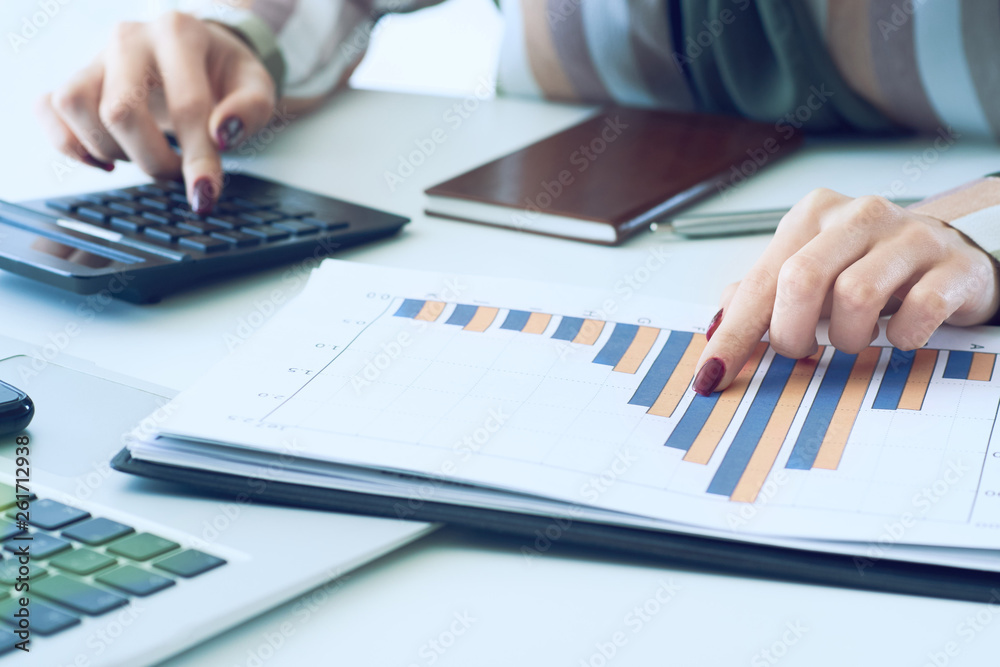 A woman's hand pointing on summary report chart and calculate finance in office close-up. A woman's hand pointing on summary report chart and calculate finance in office close-up.
