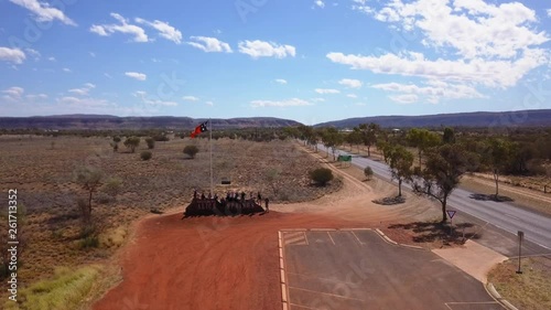 Drone zooming out from Alice Springs sign with people sitting on top of it. photo