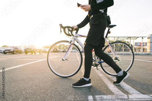 Athlete is a cyclist in sports wear walking around the city with a white bike. Man goes on a bike ride. Cyclist moves around the city on a bicycle.