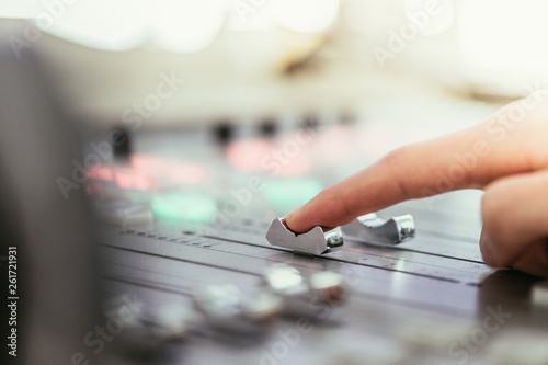 Radio broadcasting studio: Moderator is using the soundboard, computer in the background