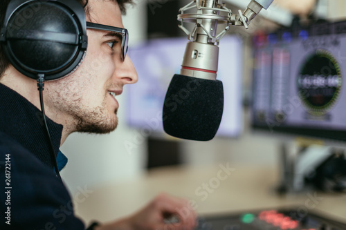 Obraz na plátně Radio moderator is sitting in a modern broadcasting studio and talking into the