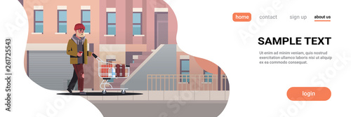 poor man pushing trolley cart with belongings beggar guy walking street begging for help homeless concept modern city buildings cityscape background horizontal full length copy space