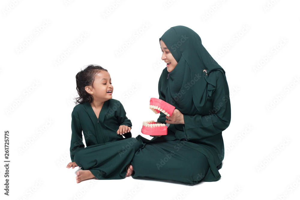 Malay mother teaching daughter on oral hygene